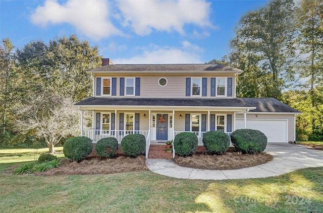 colonial home featuring a front yard, a porch, and a garage