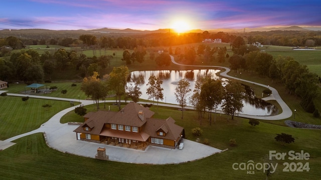 aerial view at dusk featuring a water and mountain view