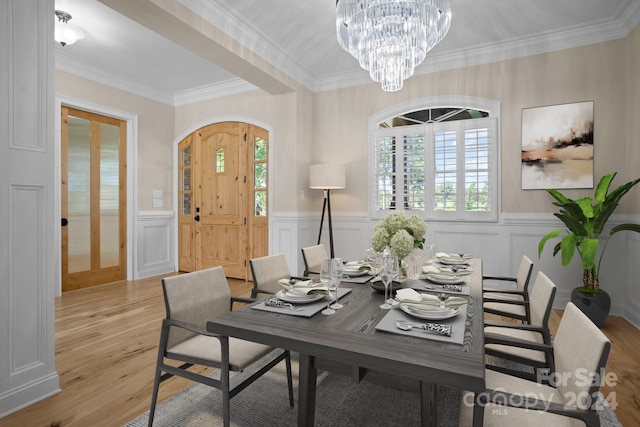 dining space featuring ornamental molding, light wood-type flooring, a wealth of natural light, and an inviting chandelier