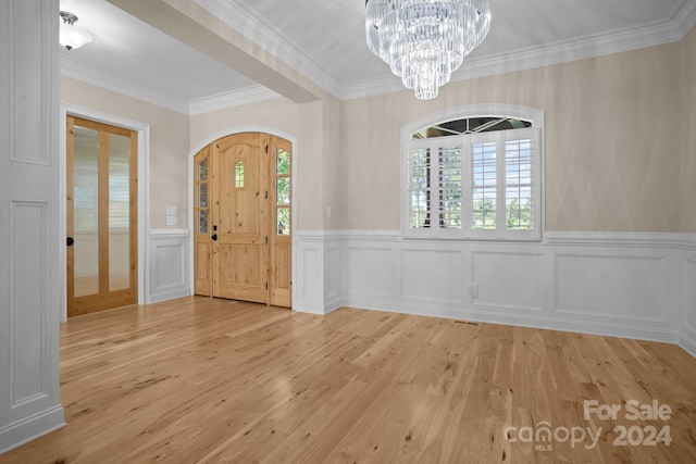 entrance foyer with an inviting chandelier, light wood-type flooring, and crown molding