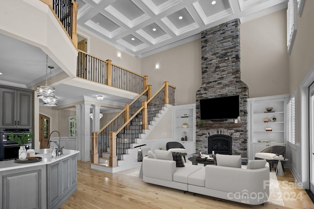 living room with a stone fireplace, a healthy amount of sunlight, a high ceiling, and coffered ceiling