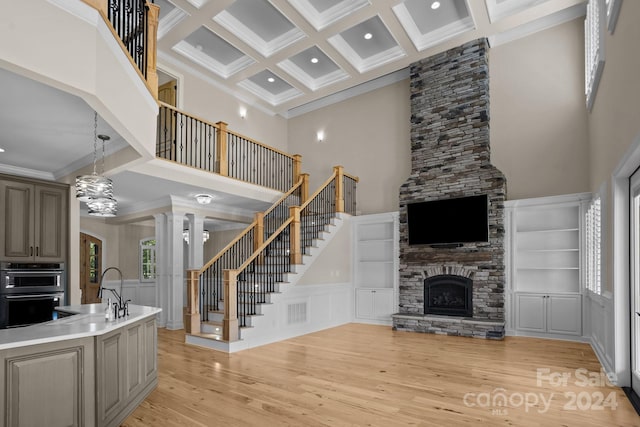 interior space featuring a stone fireplace, ornate columns, a healthy amount of sunlight, and a towering ceiling