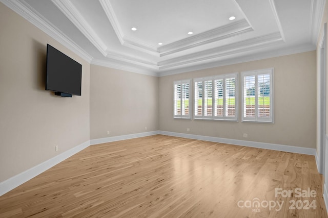 unfurnished room with light wood-type flooring, a raised ceiling, and crown molding