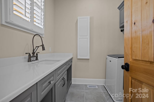 clothes washing area with cabinets, tile patterned floors, sink, and washer / clothes dryer