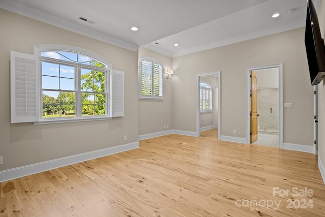 empty room featuring light wood-type flooring and ornamental molding