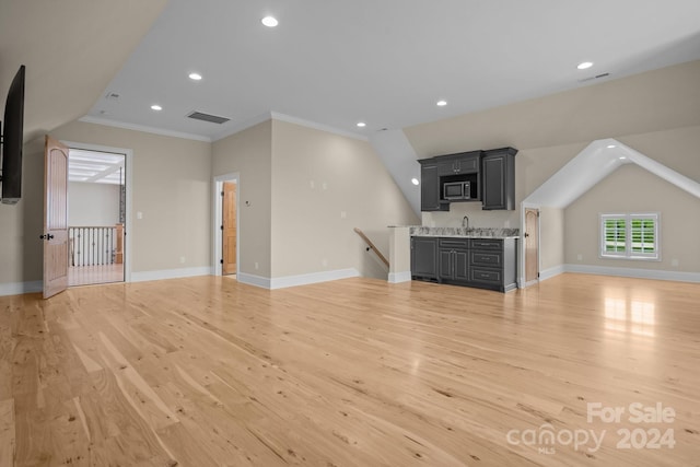 unfurnished living room featuring light hardwood / wood-style floors, sink, crown molding, and vaulted ceiling