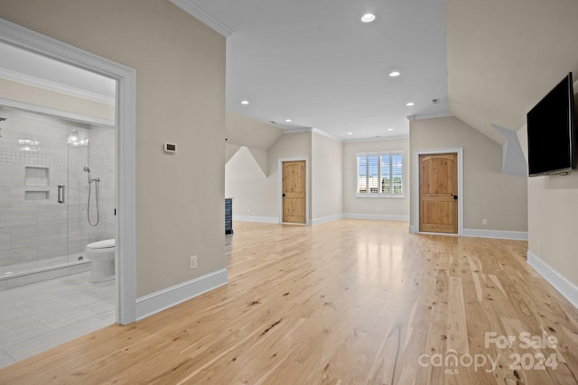 unfurnished living room featuring a chandelier, light hardwood / wood-style flooring, lofted ceiling, and ornamental molding