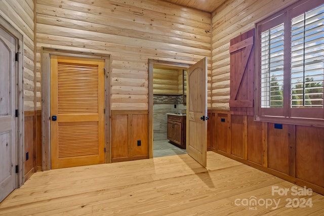 doorway with light hardwood / wood-style floors, wooden walls, and plenty of natural light