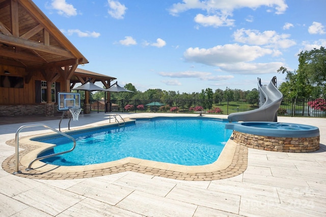 view of pool with a water slide, an in ground hot tub, and a patio area