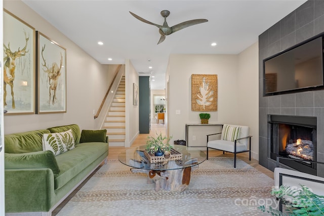 living room with light hardwood / wood-style flooring, a fireplace, and ceiling fan