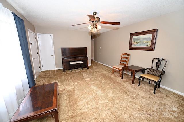 sitting room with light carpet, a textured ceiling, and ceiling fan