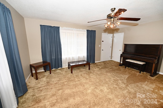 sitting room featuring a textured ceiling, carpet flooring, and ceiling fan