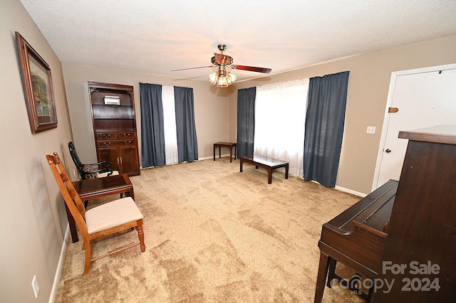 sitting room with light carpet, a textured ceiling, and ceiling fan