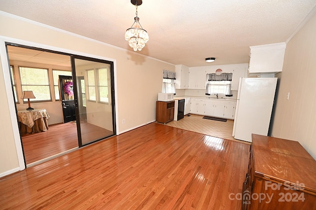 unfurnished living room featuring light hardwood / wood-style flooring, a textured ceiling, a chandelier, and crown molding