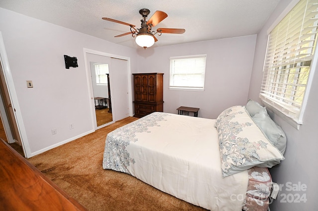 carpeted bedroom with a closet, ceiling fan, and a textured ceiling