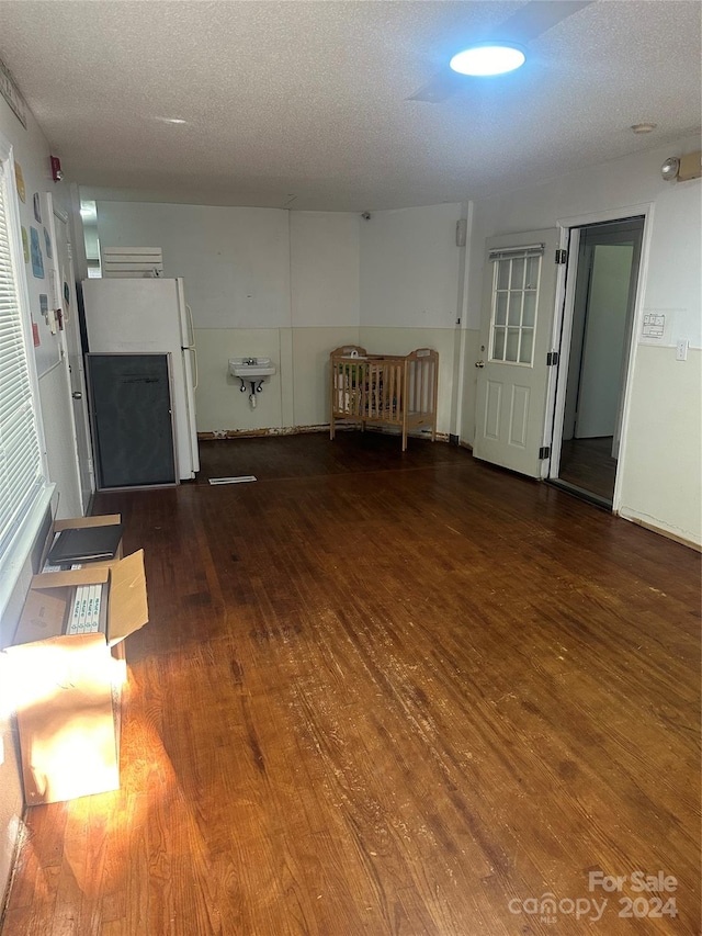 unfurnished living room with a textured ceiling and dark hardwood / wood-style flooring