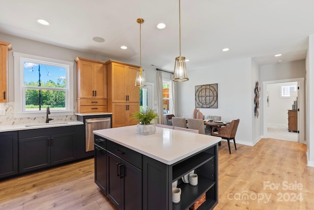 kitchen featuring a kitchen island, stainless steel dishwasher, light brown cabinetry, light wood-type flooring, and sink