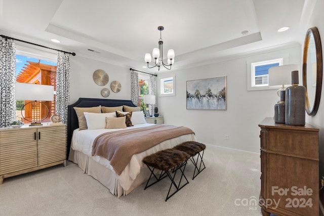 bedroom featuring a chandelier, a tray ceiling, and light colored carpet