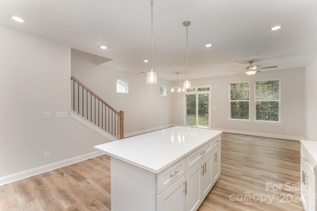 kitchen featuring white cabinetry, a center island, ceiling fan, and light hardwood / wood-style floors