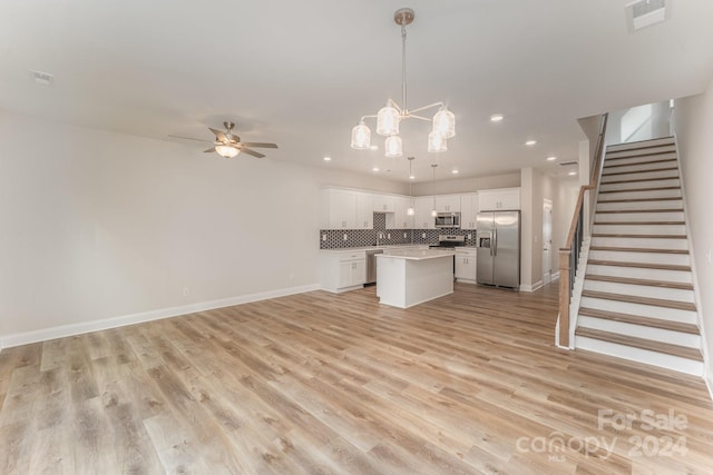 kitchen featuring white cabinetry, a center island, stainless steel appliances, decorative light fixtures, and ceiling fan with notable chandelier