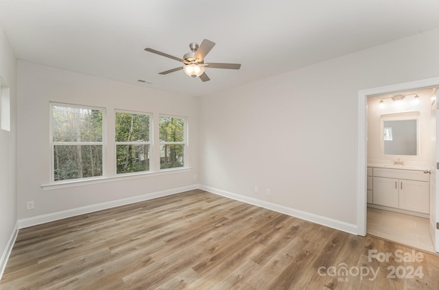 unfurnished bedroom with connected bathroom, ceiling fan, sink, and light wood-type flooring