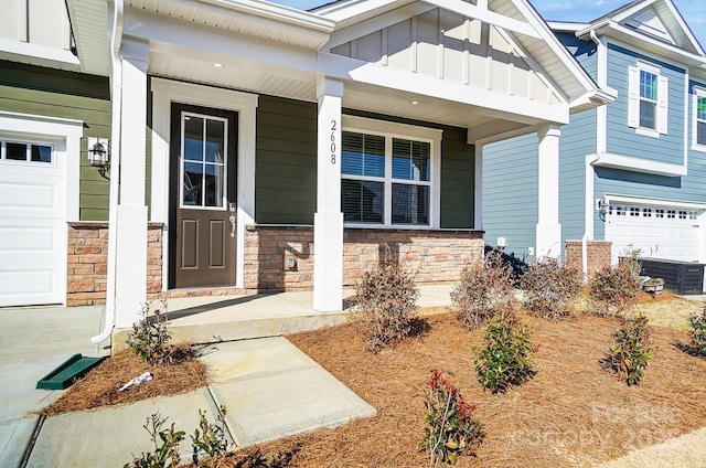 view of exterior entry featuring covered porch, stone siding, and board and batten siding