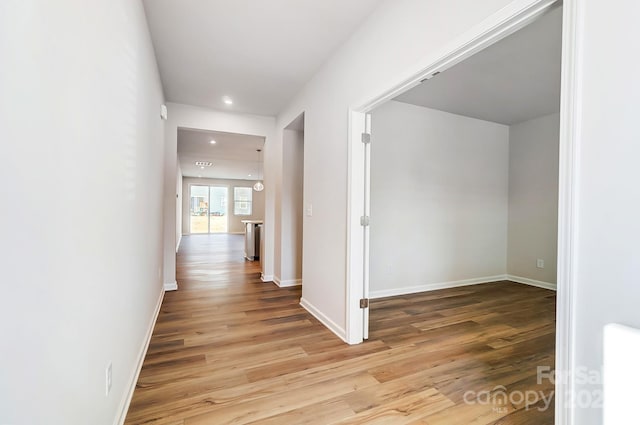 corridor with light wood-style flooring, baseboards, and recessed lighting