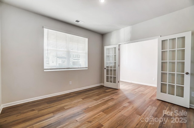 unfurnished room with french doors, wood finished floors, visible vents, and baseboards