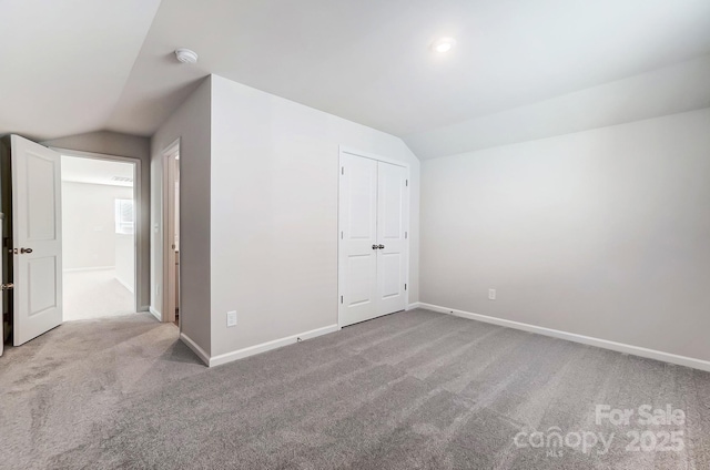 unfurnished bedroom featuring carpet floors, lofted ceiling, and baseboards