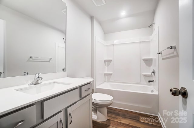 bathroom with toilet, wood finished floors, vanity, visible vents, and washtub / shower combination