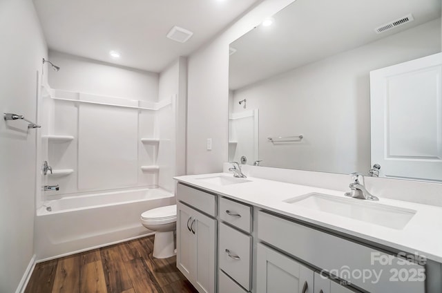 bathroom featuring toilet, wood finished floors, a sink, and visible vents