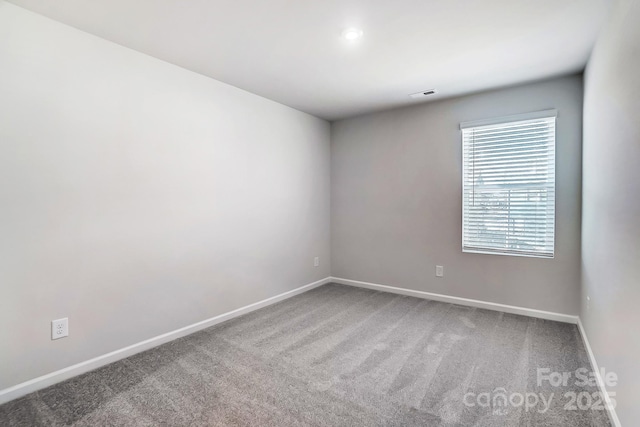 spare room with carpet, visible vents, and baseboards