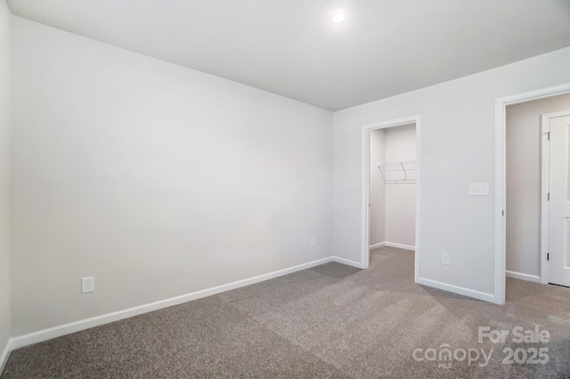 unfurnished bedroom with carpet floors, baseboards, a walk in closet, and a closet