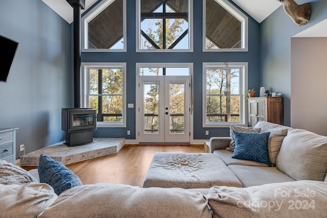 living room featuring a wood stove, hardwood / wood-style floors, high vaulted ceiling, and plenty of natural light