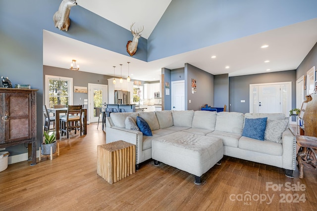 living room with high vaulted ceiling and light wood-type flooring