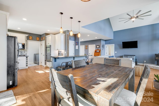 dining space with ceiling fan, high vaulted ceiling, and light wood-type flooring