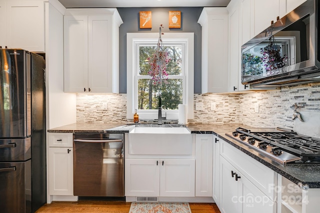 kitchen featuring appliances with stainless steel finishes, decorative backsplash, white cabinetry, and light hardwood / wood-style flooring