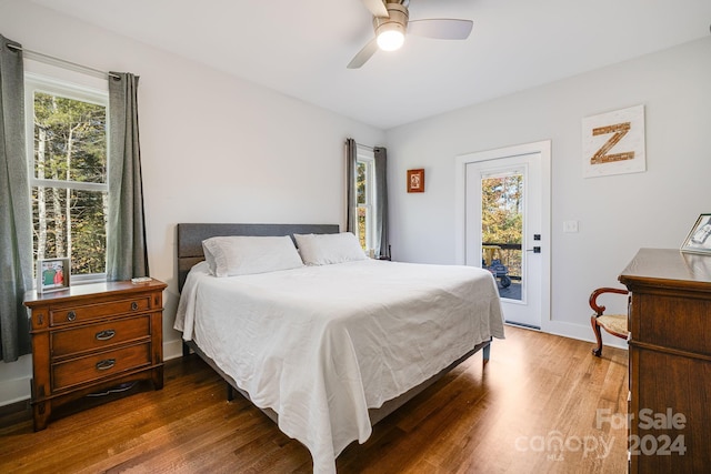 bedroom featuring dark wood-type flooring, multiple windows, access to exterior, and ceiling fan