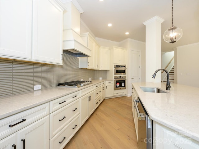 kitchen featuring sink, hanging light fixtures, light stone counters, stainless steel appliances, and custom range hood