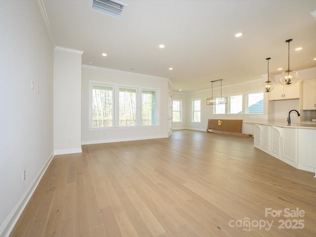 unfurnished living room with crown molding, sink, and light hardwood / wood-style flooring