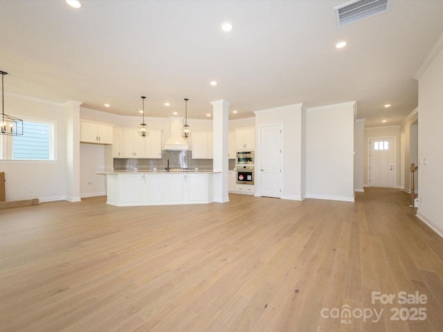 unfurnished living room featuring ornamental molding, sink, light hardwood / wood-style flooring, and a wealth of natural light