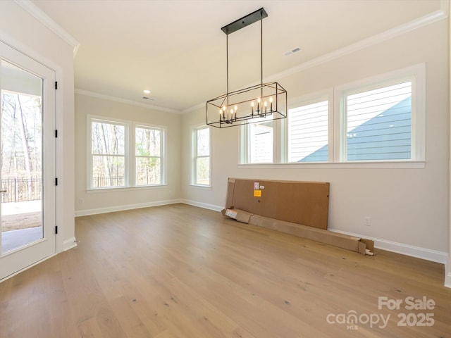 unfurnished dining area featuring an inviting chandelier, hardwood / wood-style floors, and crown molding