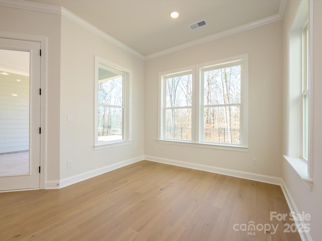 empty room featuring crown molding, a healthy amount of sunlight, and light wood-type flooring