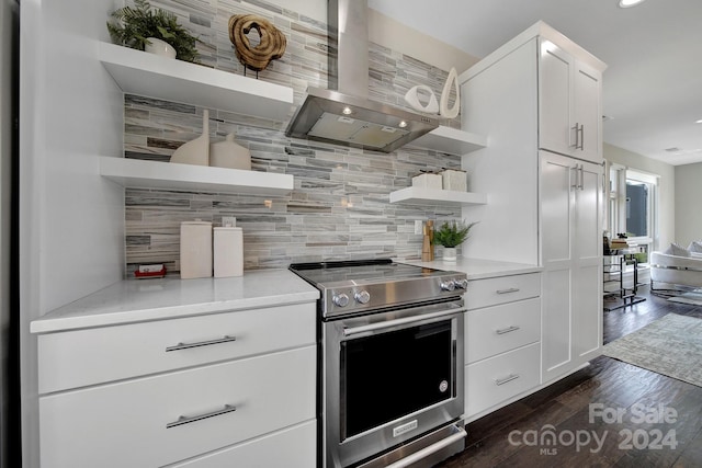 kitchen featuring wall chimney range hood, stainless steel electric stove, decorative backsplash, white cabinetry, and dark hardwood / wood-style floors