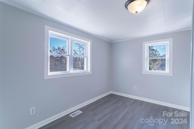 empty room with dark wood-type flooring and crown molding