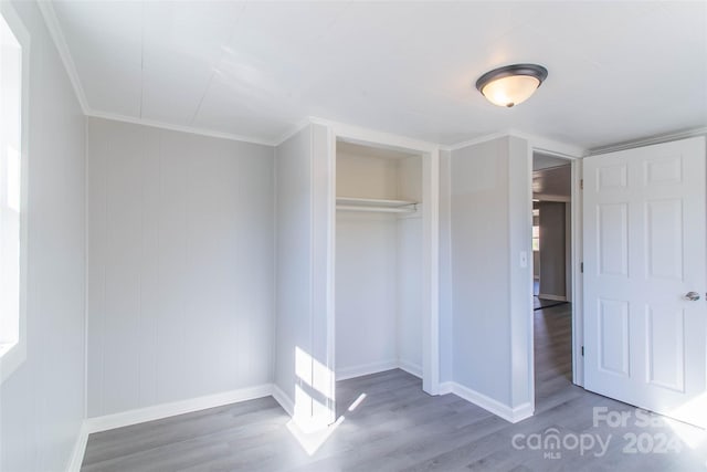 unfurnished bedroom featuring crown molding, hardwood / wood-style flooring, and a closet