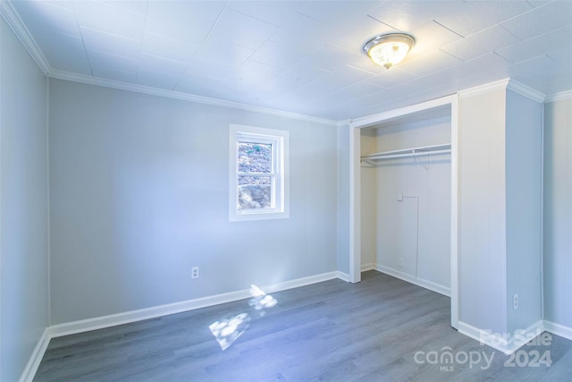 unfurnished bedroom with ornamental molding, a closet, and hardwood / wood-style floors