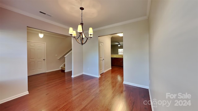 unfurnished dining area featuring ornamental molding, wood-type flooring, and ceiling fan with notable chandelier