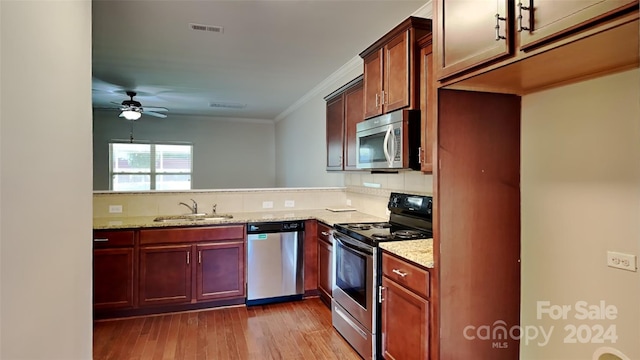 kitchen featuring stainless steel appliances, crown molding, sink, light stone countertops, and light wood-type flooring