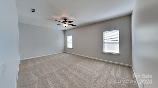 carpeted spare room featuring ceiling fan and a wealth of natural light